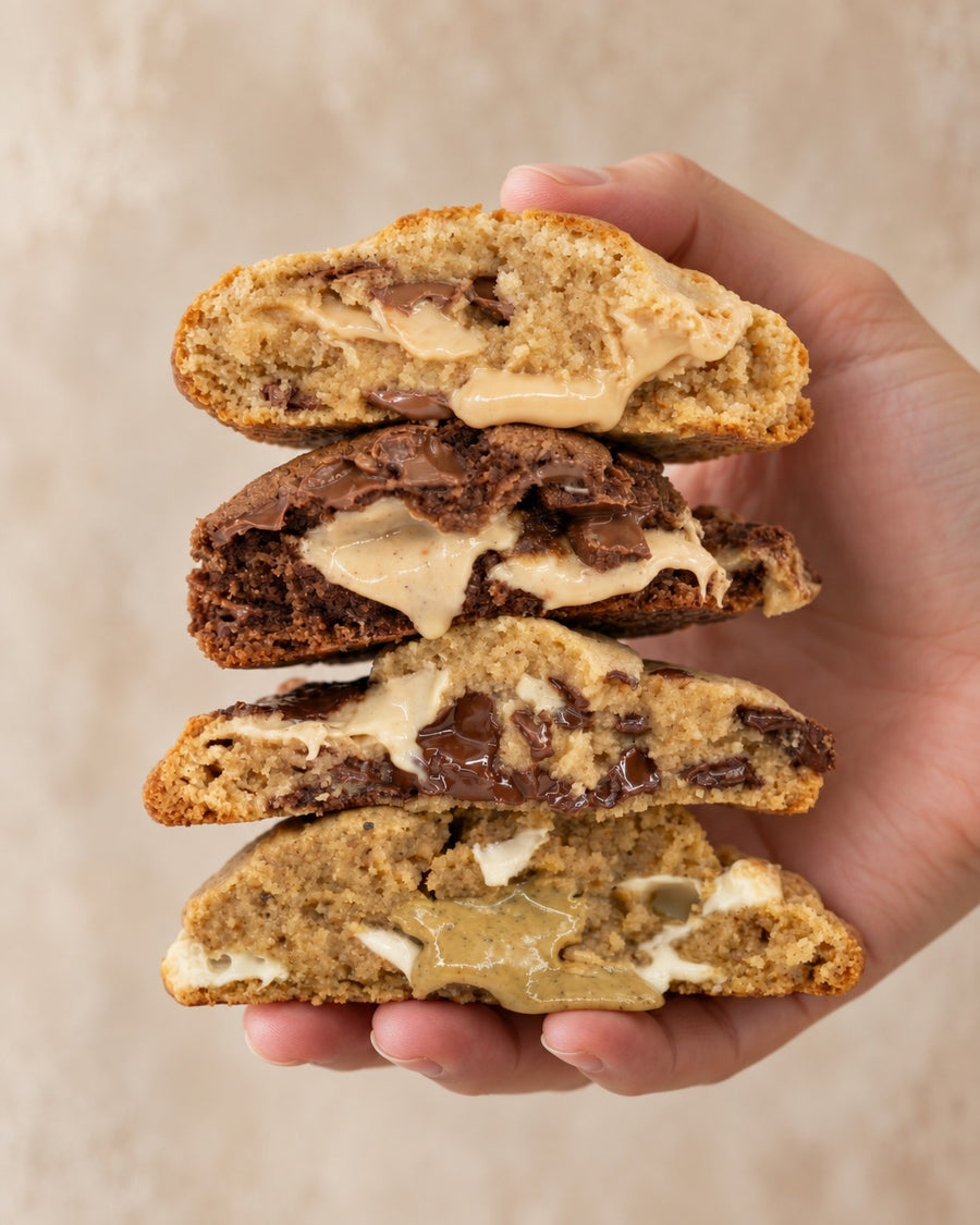 Cuatro cookies sin gluten de frutos secos abiertas por la mitad, con el relleno fundido